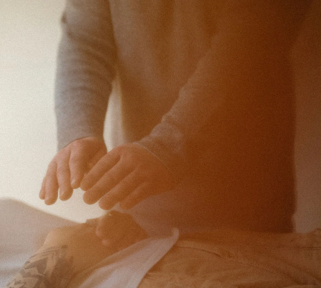 Hands held above a client during a Reiki session at Ramaste